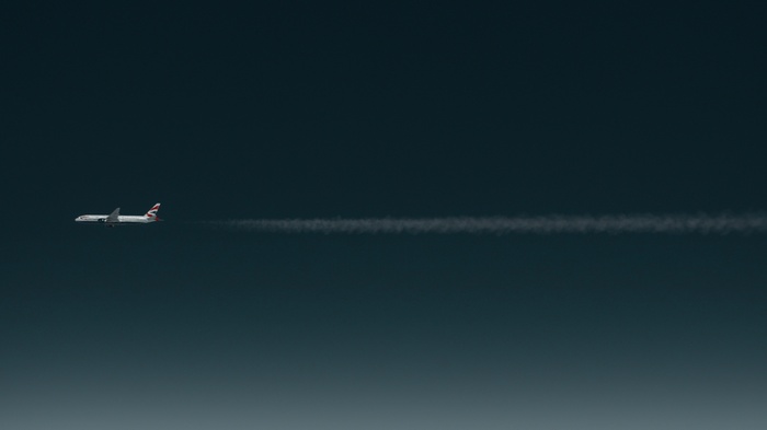 British Airways airplane flying through the sky leaving contrails
