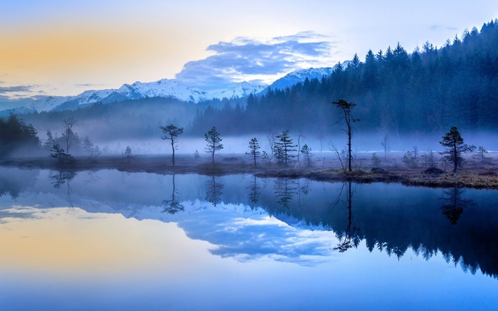 Misty lake with reflections of mountains and forest