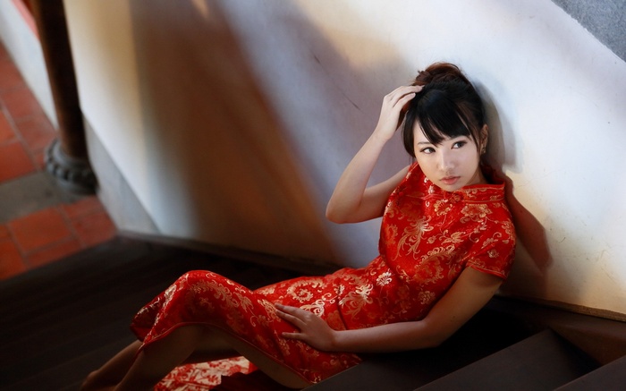 Woman in a red Cheongsam dress sitting on stairs