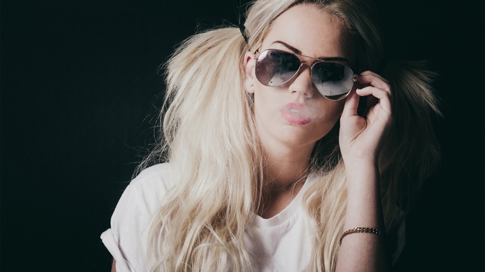 Woman with blonde pigtails and sunglasses smoking
