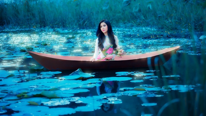 Asian woman in a boat with lotus flowers