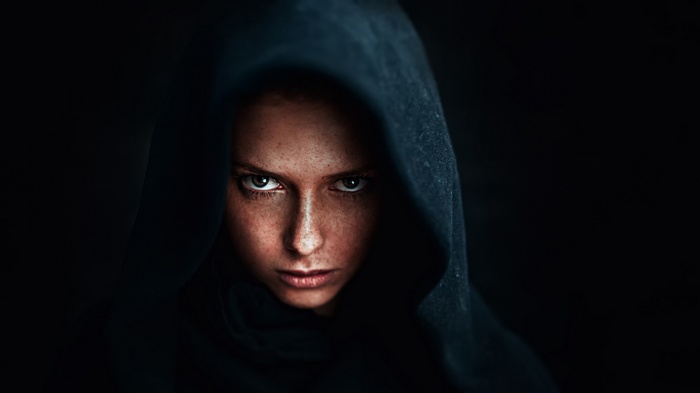 Woman in a dark hood looking intensely