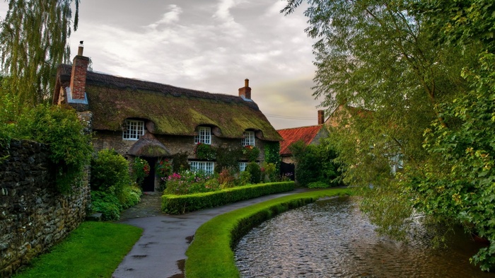 Thatched cottage by a stream in a village