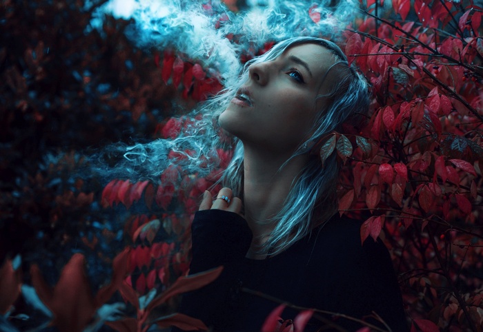 Woman smoking in a forest with red leaves