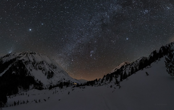 Starry night sky over snow-covered mountains