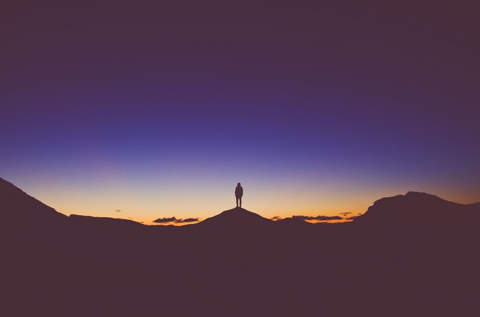 Silhouette of a person on a hilltop at sunset