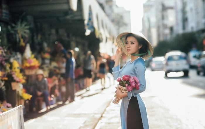 Woman in Ao Dai holding flowers in Vietnam
