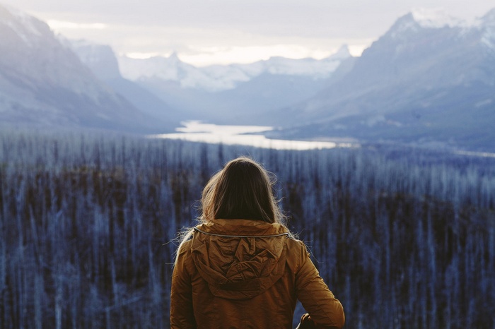 Woman in yellow jacket overlooking mountains and lake