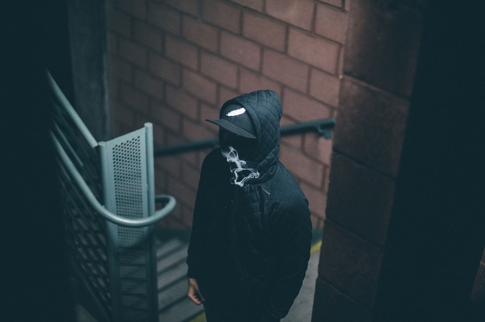 Person in a hooded jacket and hat with smoke
