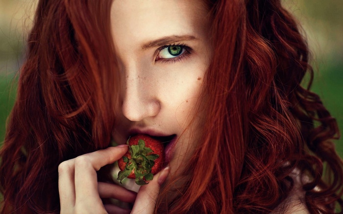 Redhead woman eating a strawberry