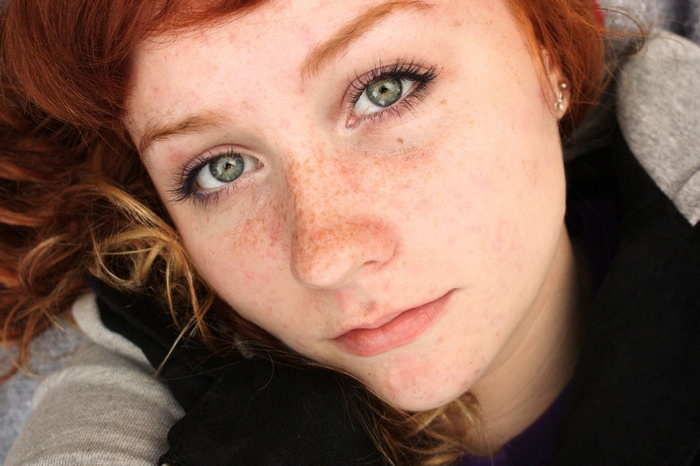 Young woman with red hair and freckles looking at the camera