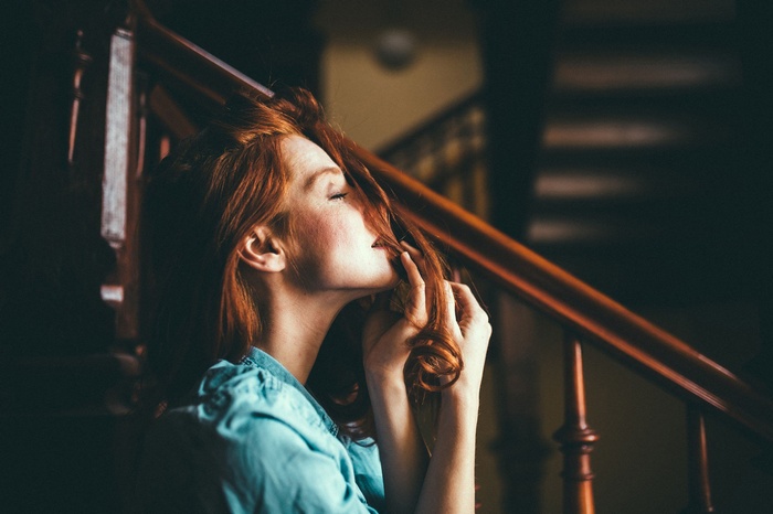 Redhead woman with eyes closed on stairs