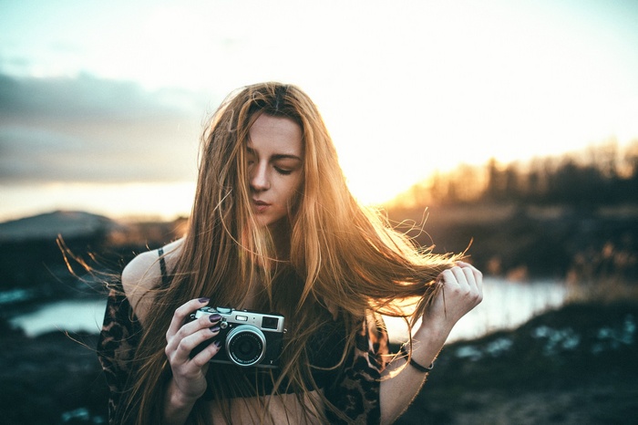 Woman holding a camera outdoors at sunset