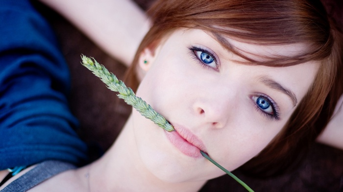 Woman with blue eyes holding a wheat stalk