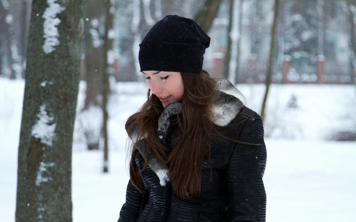 Woman in black beanie and jacket in winter park