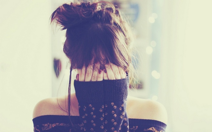Woman covering face with hands and sweater