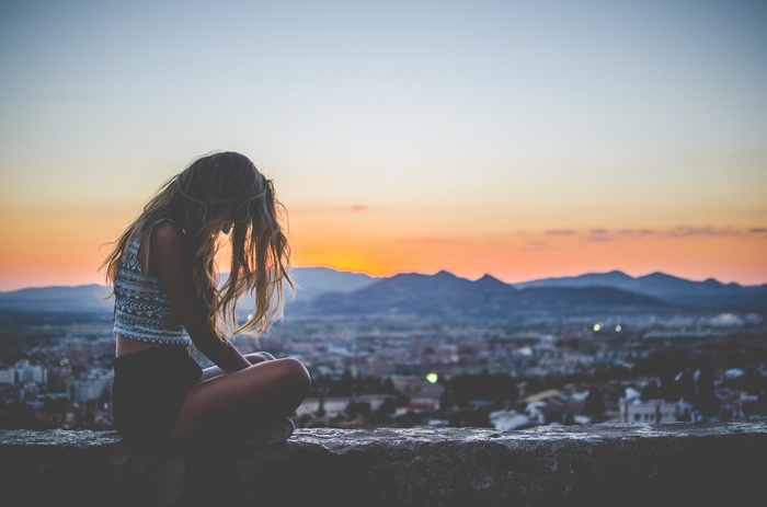 Woman with long hair sitting at sunset overlooking city