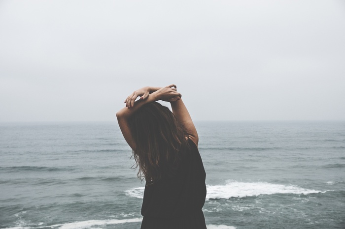 Woman with hands on head by the ocean
