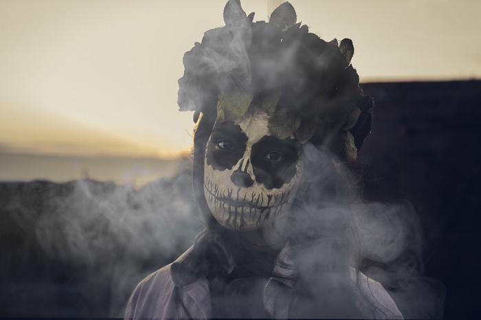 Woman with skull face and flower crown in smoke