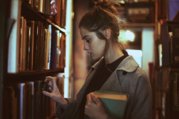 Woman in grey coat browsing books in a library