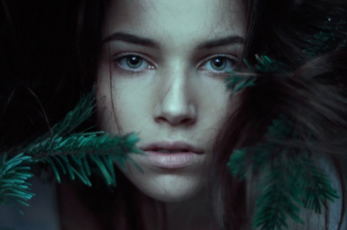 Close-up portrait of a young woman with pine branches