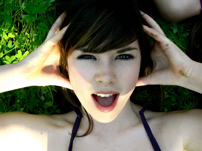 Woman lying on grass with hands on head