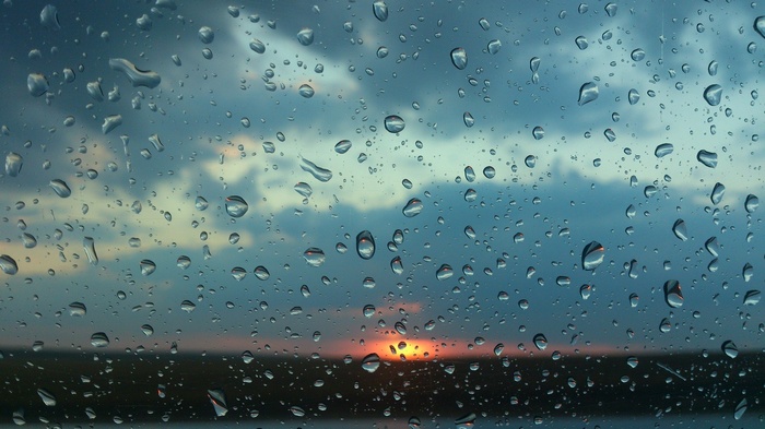 Raindrops on glass with sunset and clouds