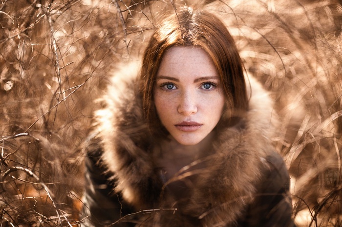 Woman with red hair and blue eyes in a fur coat