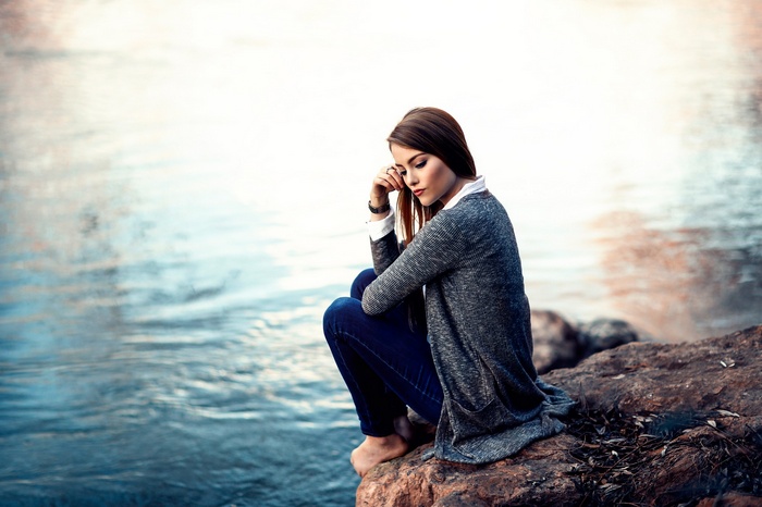 Woman sitting on rocks by the water