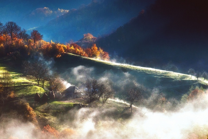 Misty mountain landscape with autumn trees and a hut