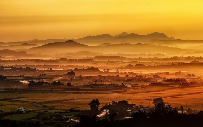 Misty valley with layered mountains at sunrise