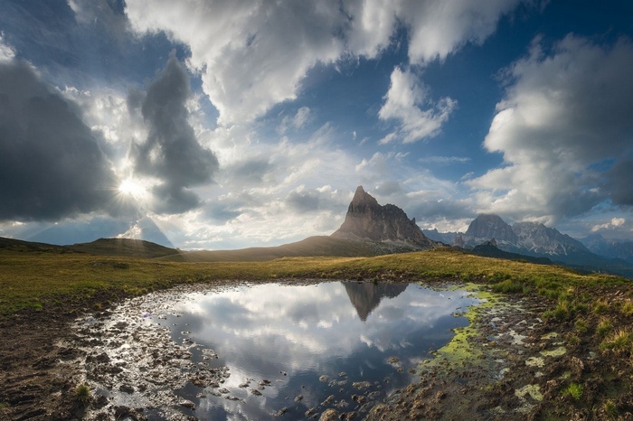 Mountain reflection in a pond with sun rays through clouds