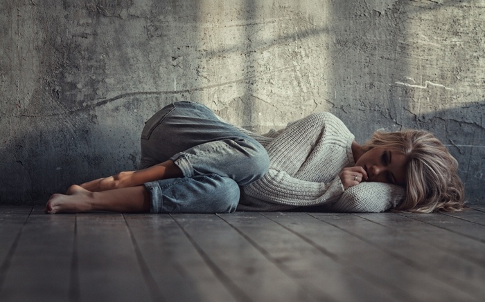 Woman lying on the floor by a wall