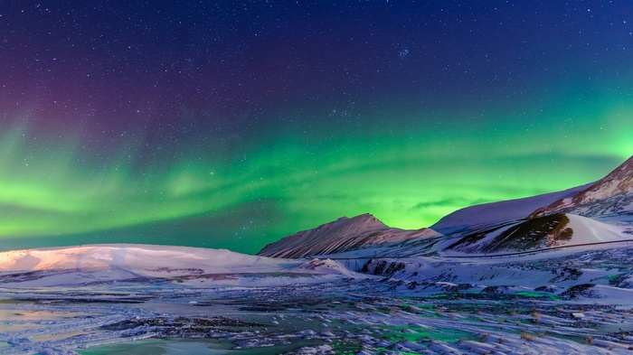Aurora Borealis over snowy mountains in Norway