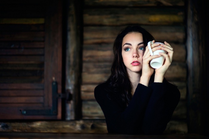 Woman holding a cup in a wooden cabin