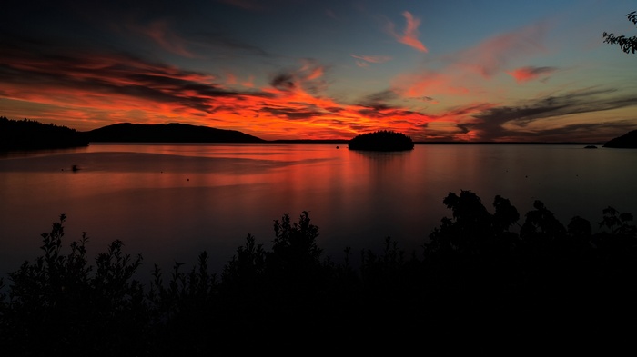Sunset over a calm lake with silhouetted trees