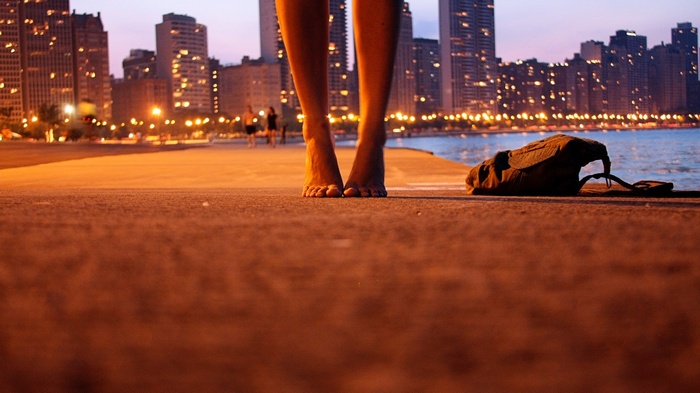 Barefoot woman on a pier with Chicago skyline at dusk