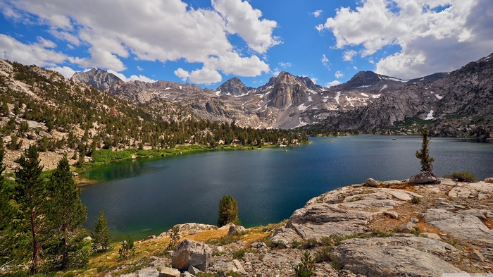 Mountain lake landscape with pine trees and clouds