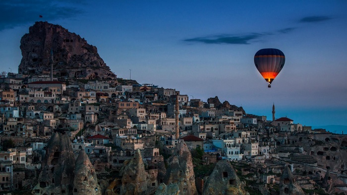 Hot air balloon over ancient city at dusk