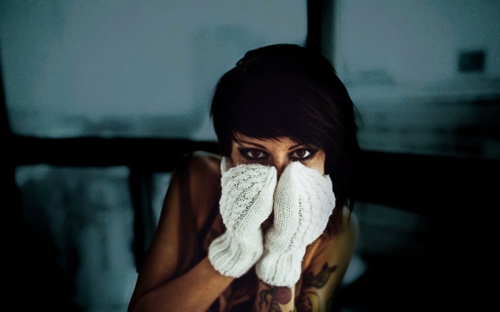 Woman with short hair wearing white mittens and tattoos