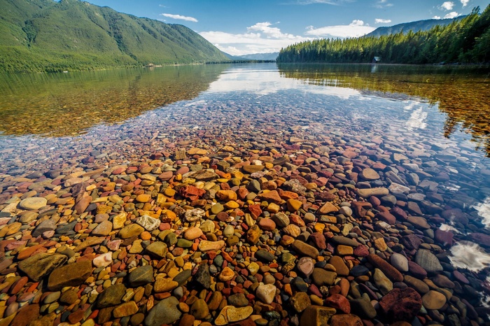Lake with colorful pebbles and mountains in Glacier National Park