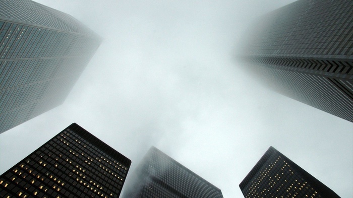 Skyscrapers shrouded in mist, viewed from below