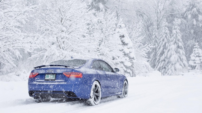 Blue Audi RS5 driving in a snowstorm