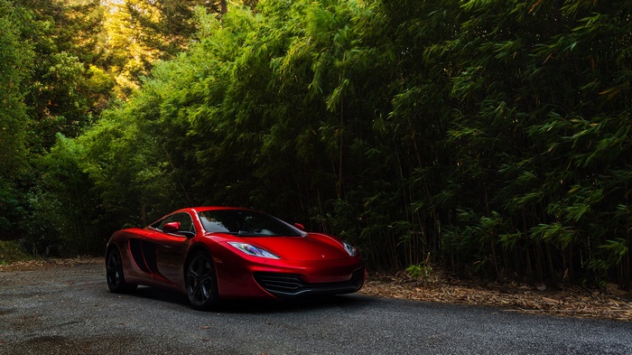 Red McLaren MP4-12C parked on a road with bamboo forest