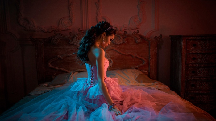 Woman in a pink corset dress on a bed