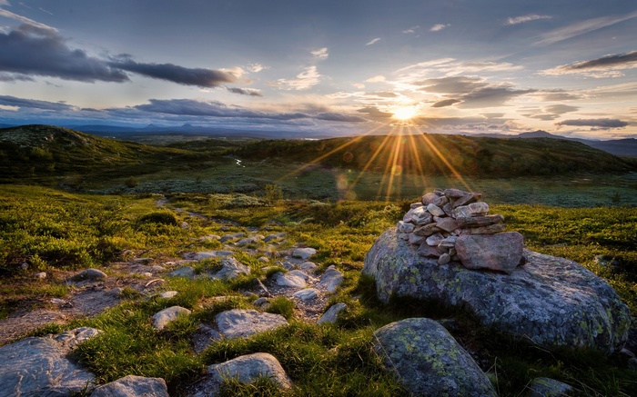 Sun setting over a rocky, grassy landscape