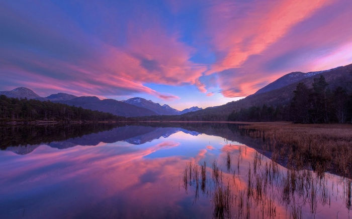 Sunset over a lake with mountains and clouds