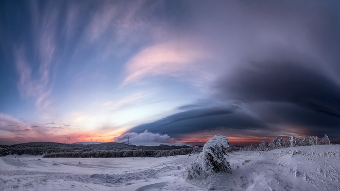 Snowy landscape with dramatic clouds at sunset