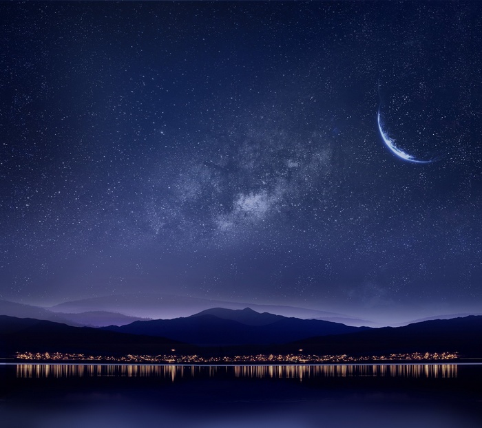 Night sky with crescent moon and Milky Way over mountains and lake