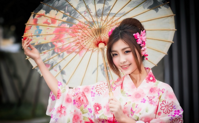 Asian woman in a pink kimono holding a floral umbrella